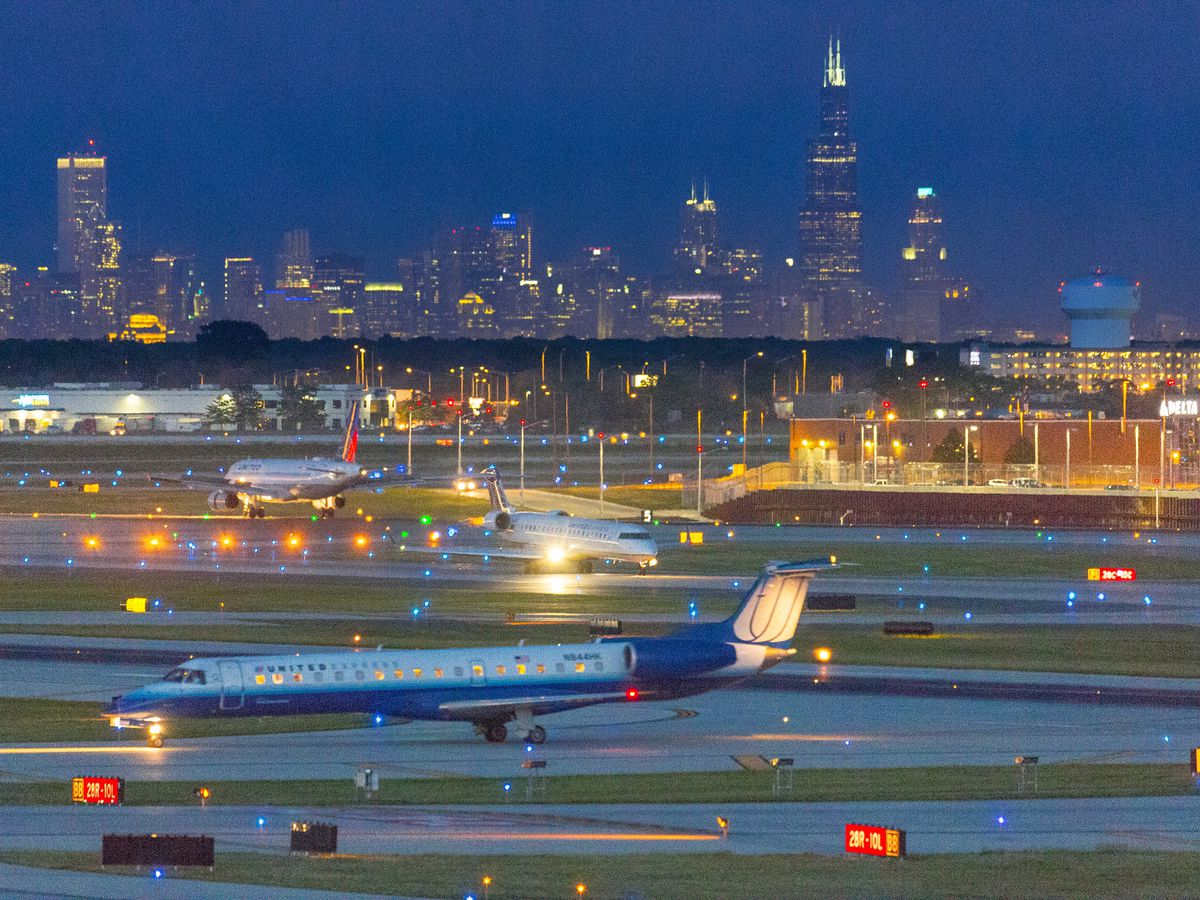 An airfield lit up at night with Chicago’s skyline in the background.