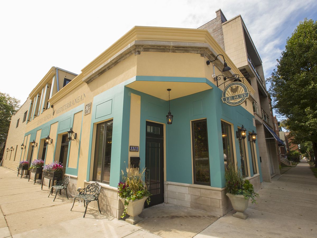 A restaurant painted turquoise and cream on a shady street corner