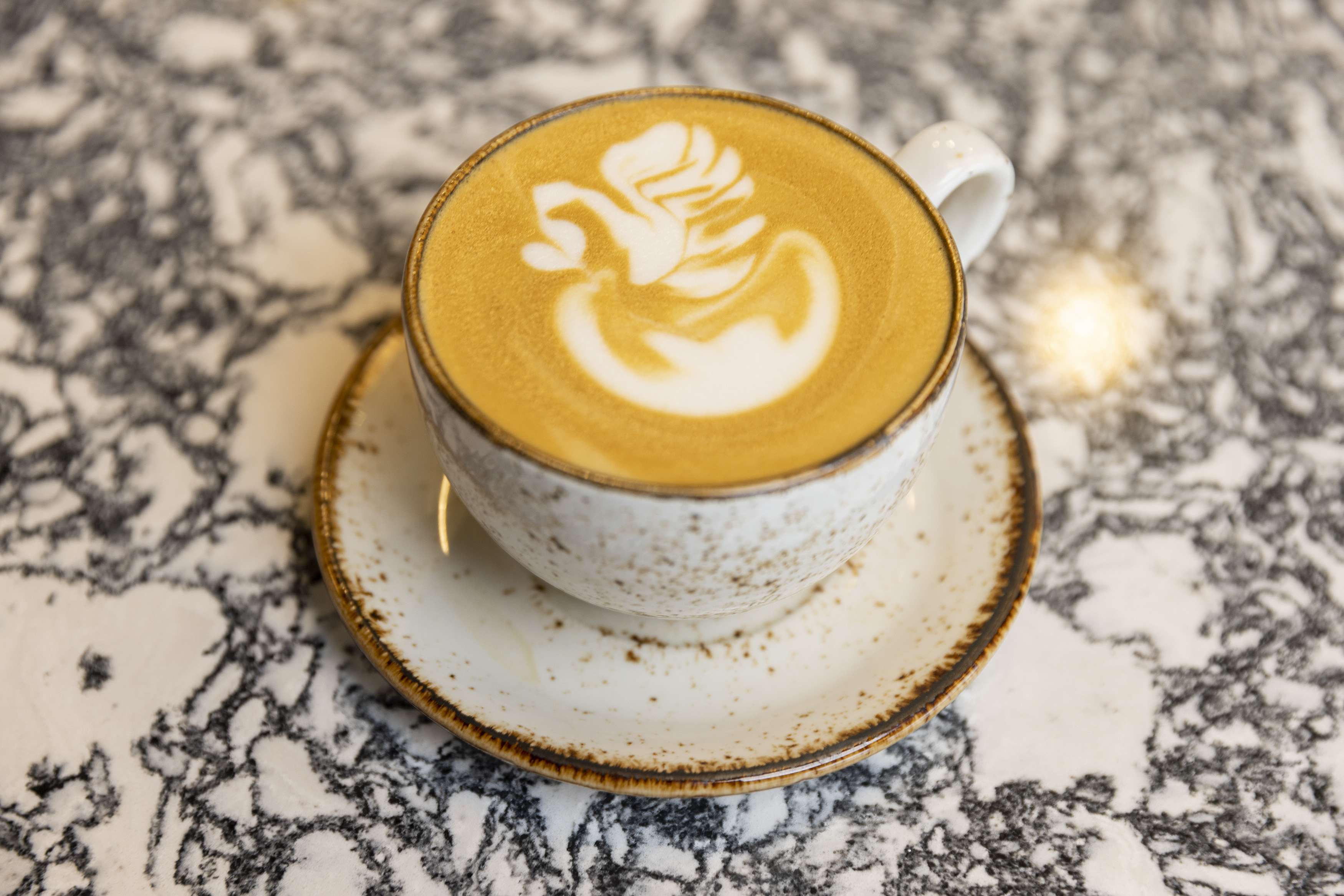A latte in a mug on a marble table.