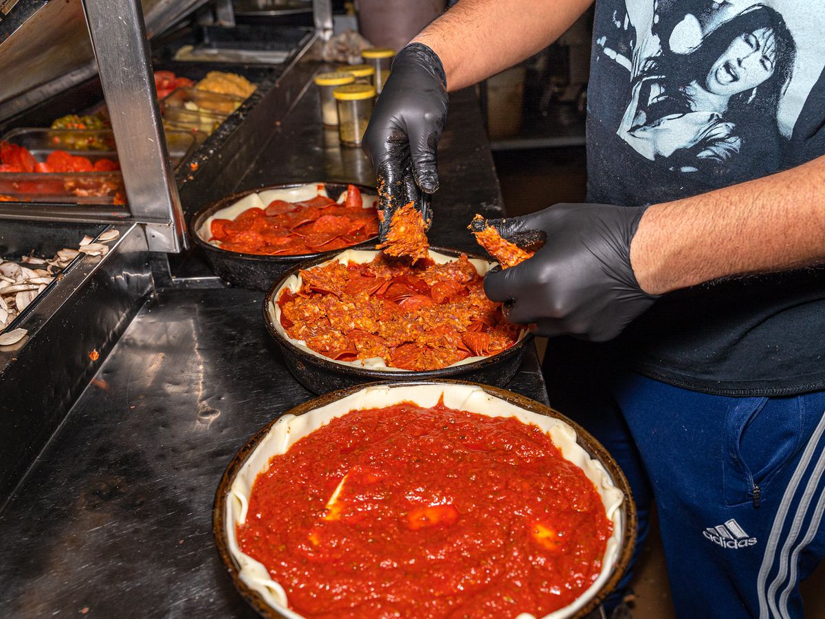 A kitchen with staff making Chicago deep-dish pizza.