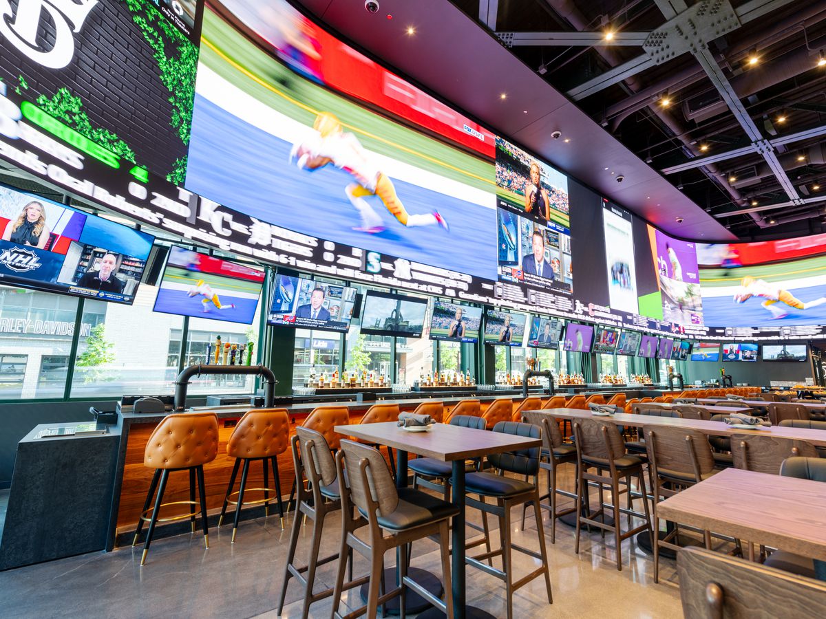 A long bar space with walls entirely covered in TV screens.
