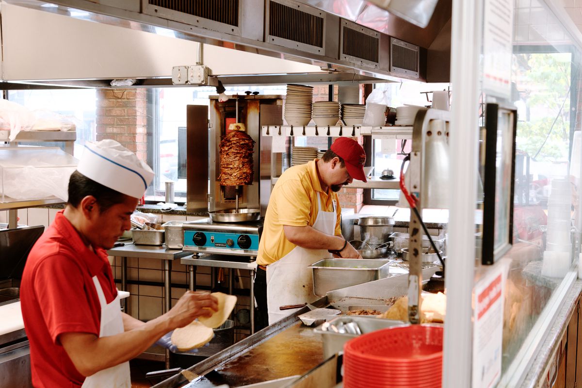 Two cooks work inside an open kitchen at Taqueria Los Gallos.