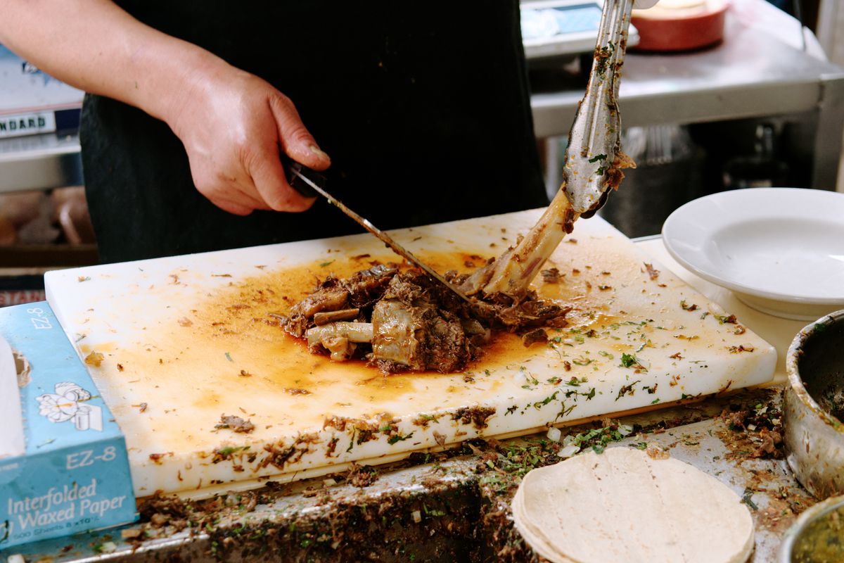 A cook cuts birria meat off the bone.