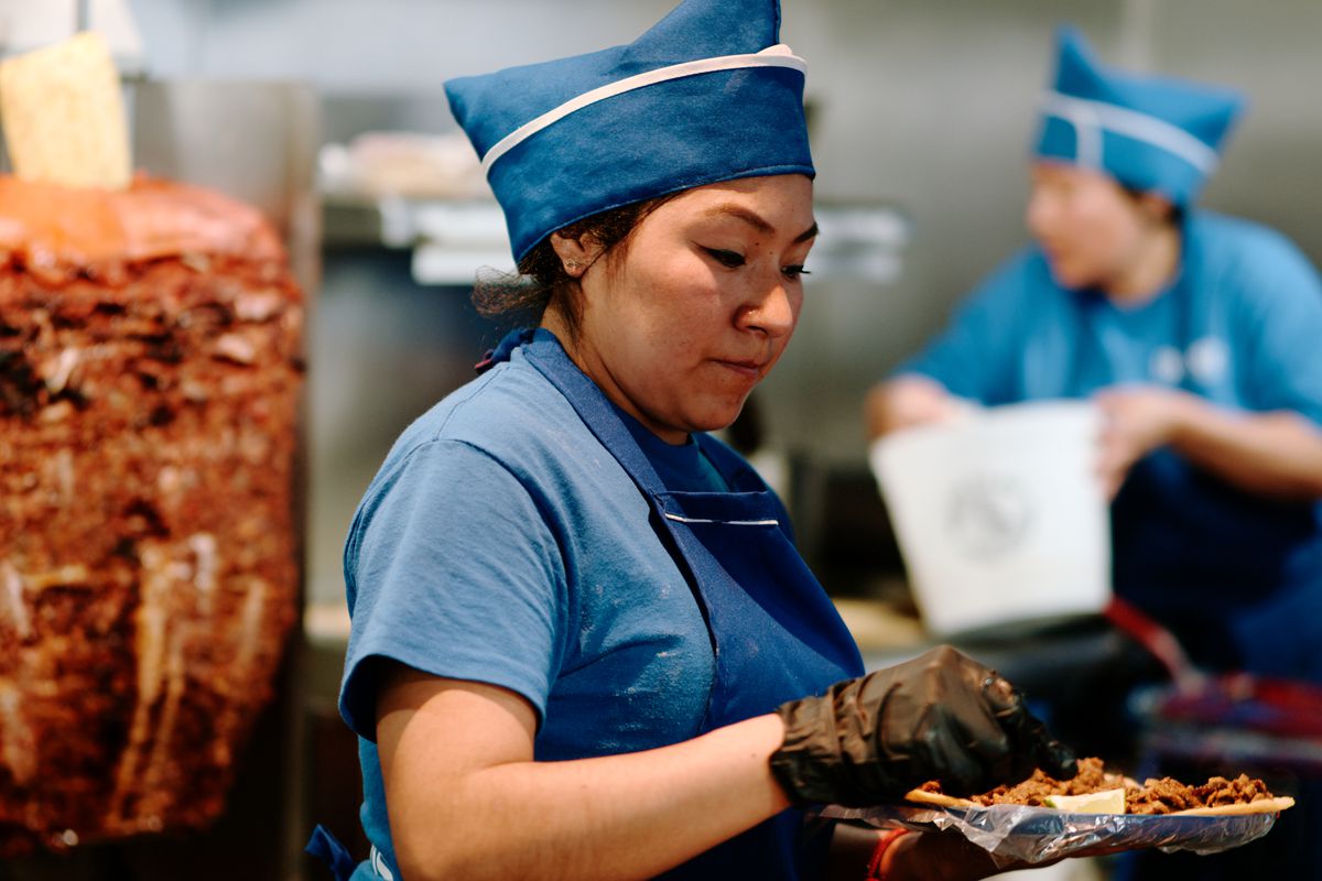 A restaurant worker in a blue hat and apron.