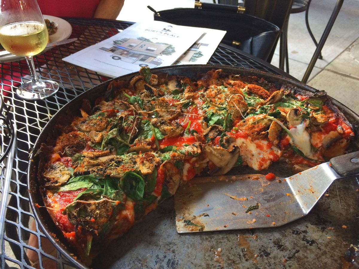 A half portion of pizza in a pan sitting on a patio table.