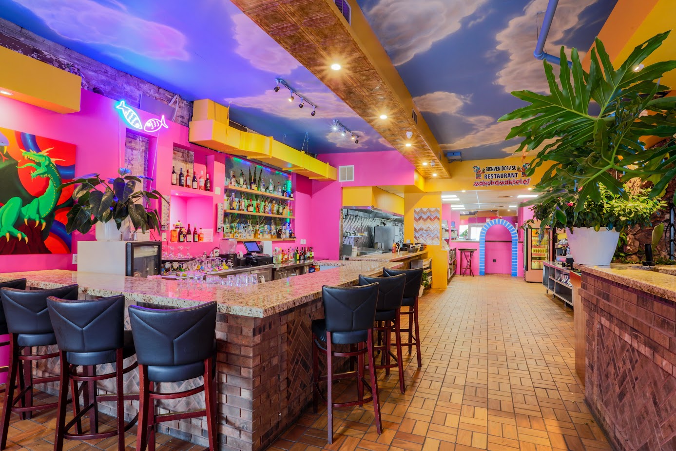 A bar section of a restaurant with bright pink and yellow walls.