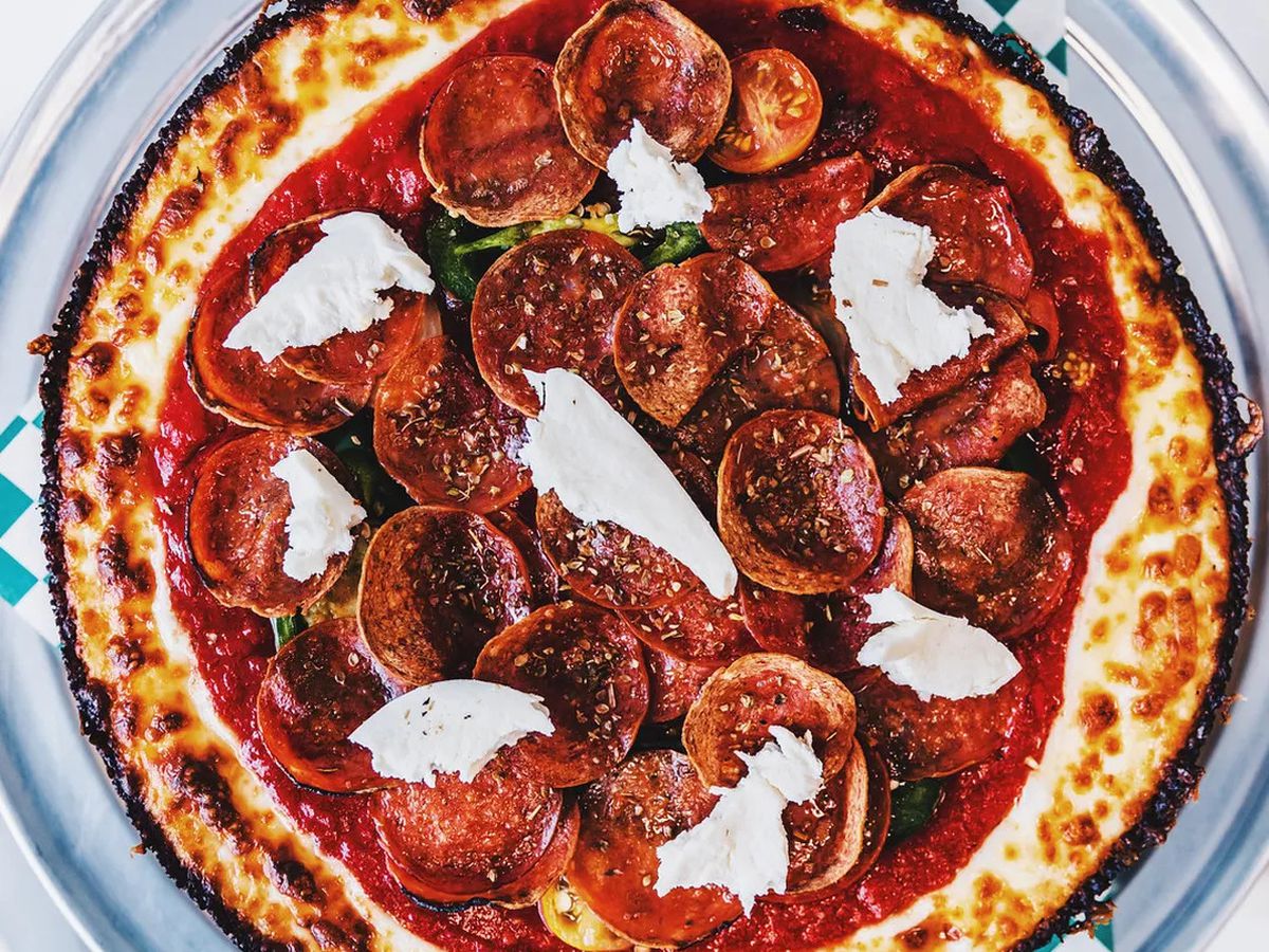 A deep dish pizza topped with pepperoni, tomatoes, and fresh mozzarella.