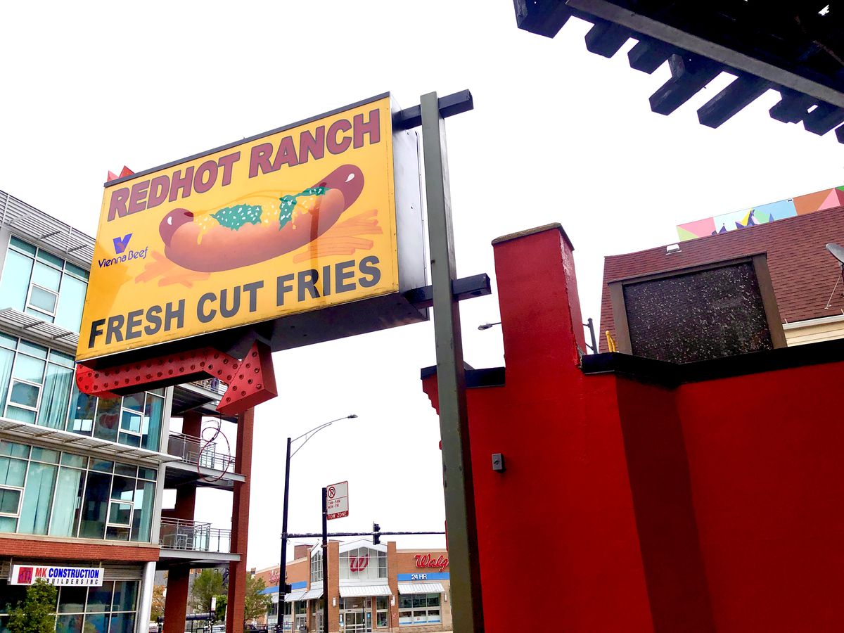 A sign for Redhot Ranch with a large hot dog and text that reads “Redhot Ranch Fresh Cut Fries”