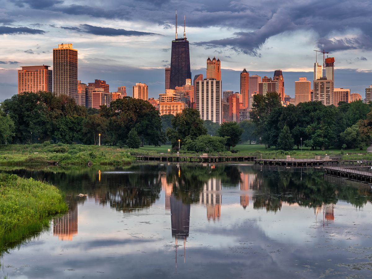 The Chicago skyline from Lincoln Park with the buildings reflecting from the lagoon during dusk.